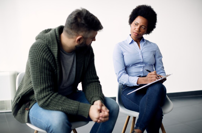 Adult in therapy session with a psychologist taking notes