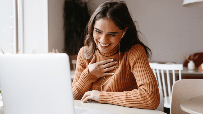 A person sitting at a table using a laptop during a telehealth psychology session.